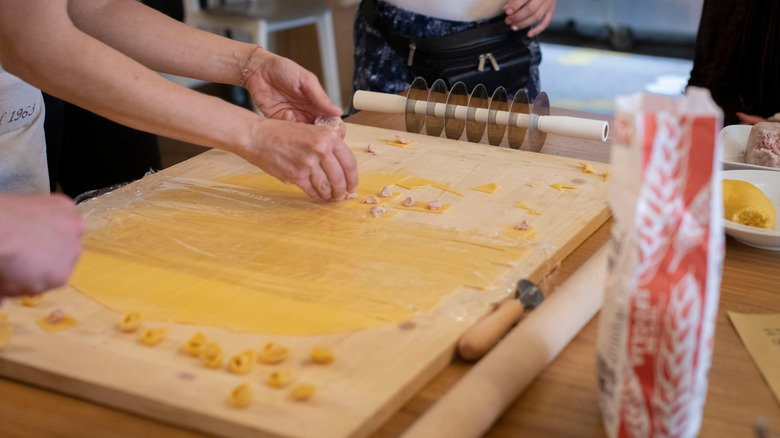 Hands shaping pasta on pasta board