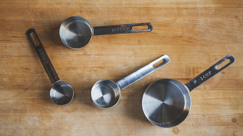 A set of metal measuring cups on a kitchen table
