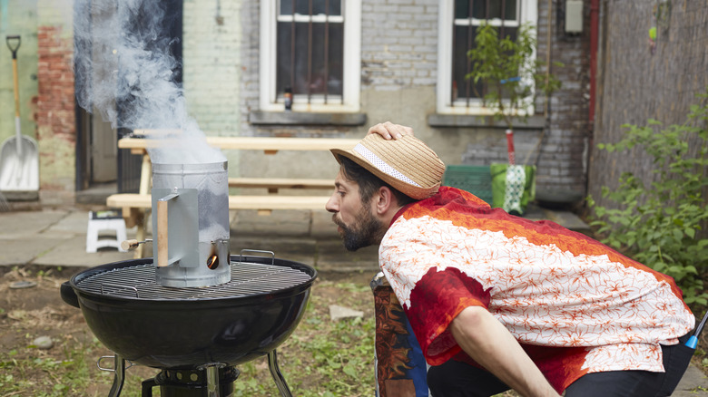 Man blowing on grill with charcoal starter