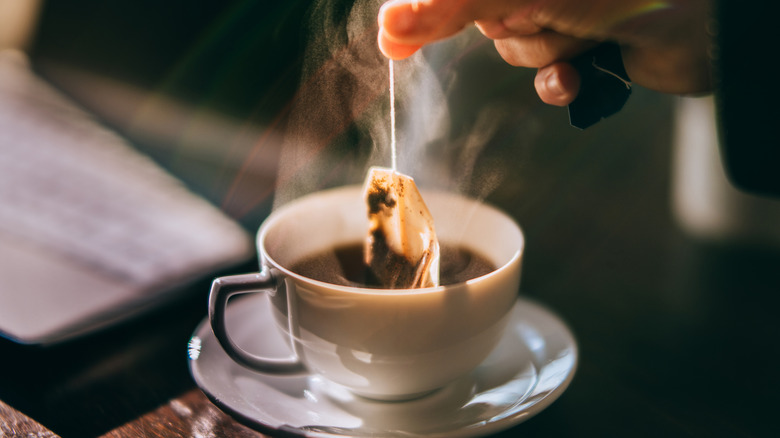 Tea bag being taken out of a cup of tea