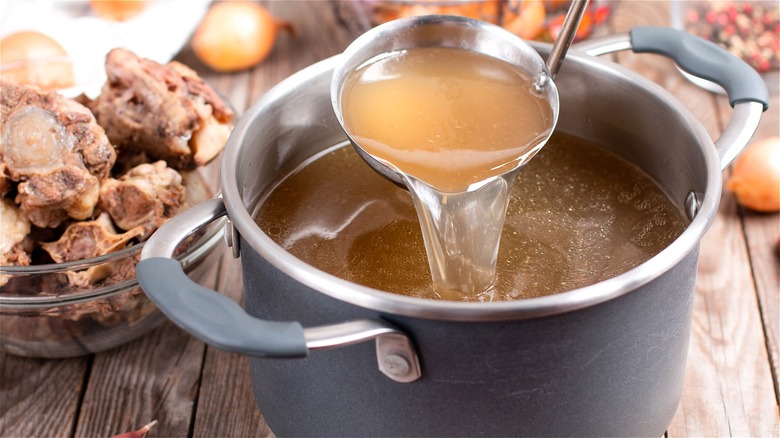 Pot with chicken stock and ladle 