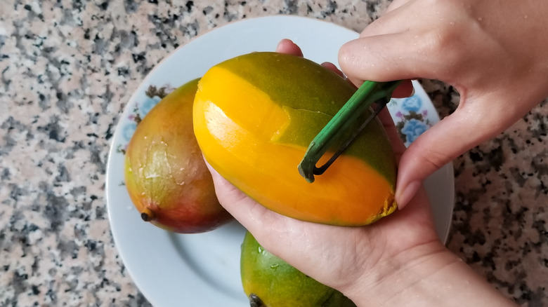 Woman peeling a mango