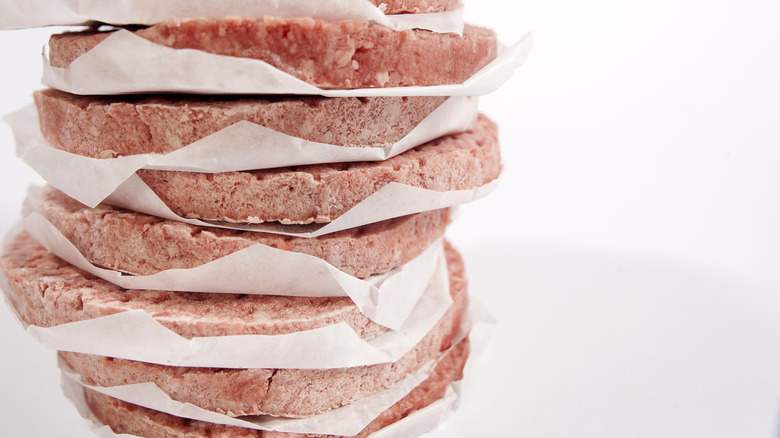 Frozen burgers separated by pieces of parchment paper