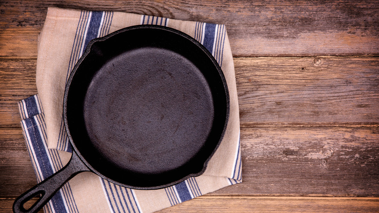 Empty cast iron skillet sitting on a tea towel
