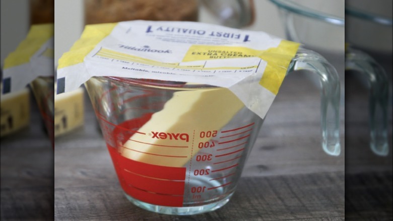 Butter wrapper covering a measuring cup with a stick of butter inside