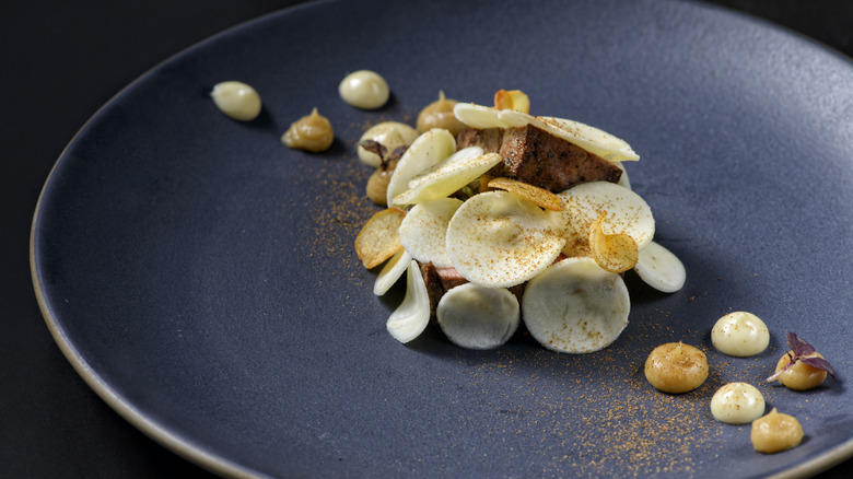 A fancy plate of food with drops of sauce on it