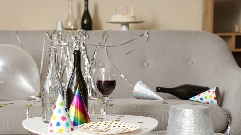 A glass of wine and bottles on a table at a party