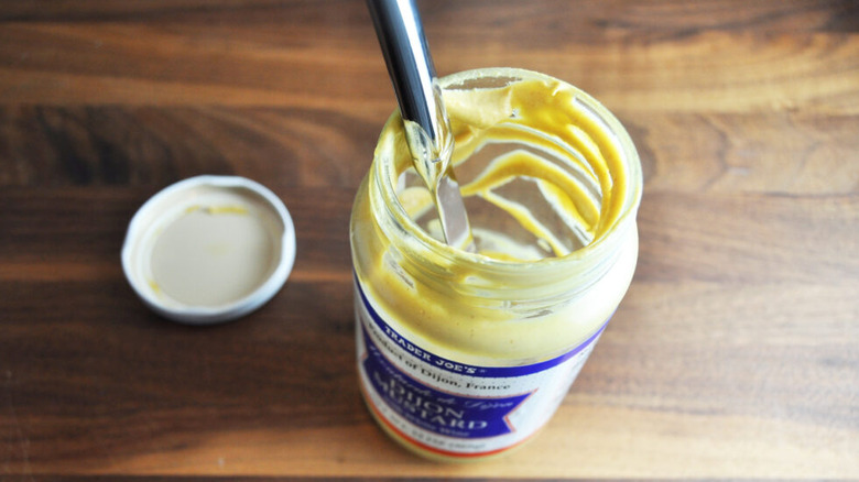 Knife in a near-empty jar of mustard