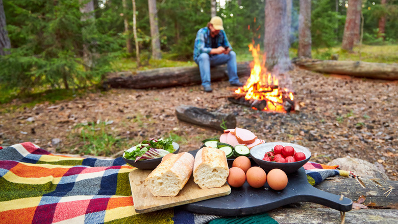 man preparing ingredients near a campfire