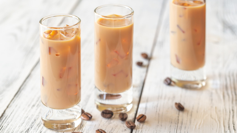 Three shots of Irish cream liqueur on a table with coffee beans