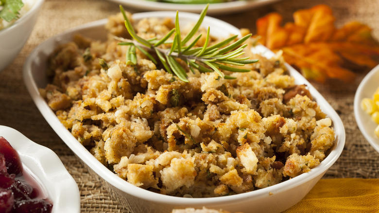 Classic stuffing served in a white dish with a sprig of rosemary garnish.