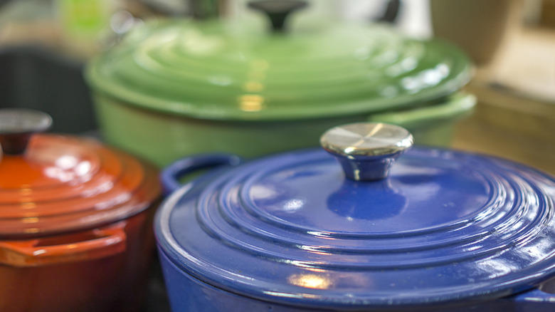 Closeup of a blue French oven's lid, with more French ovens in the background