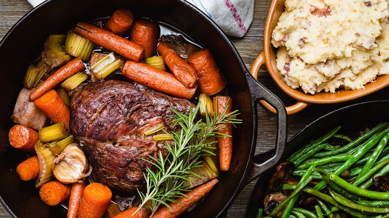 Pot roast in a Dutch oven with mashed potatoes and green beans