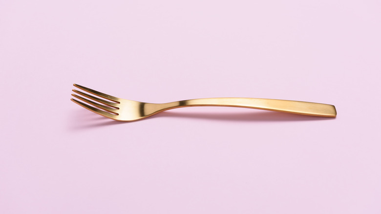 gold fork on pink background
