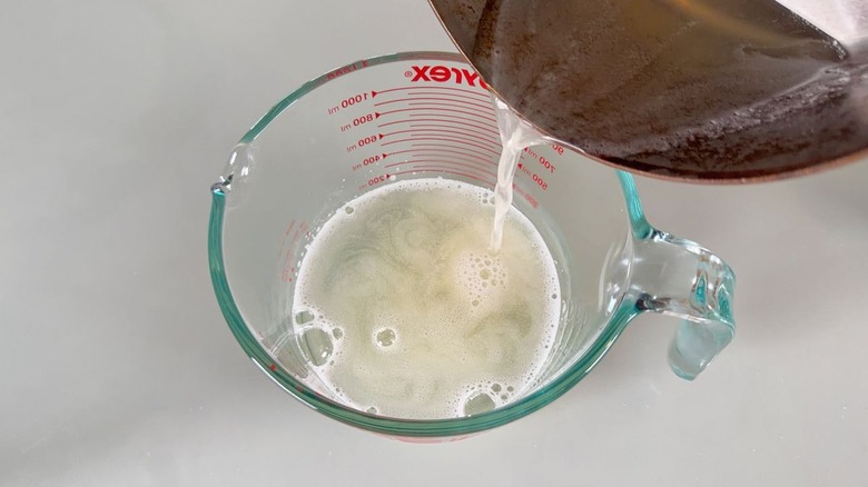Pouring warm gelatin and soda mixture into glass measuring pitcher