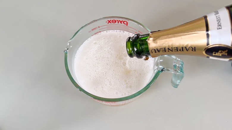Pouring champagne into glass measuring pitcher
