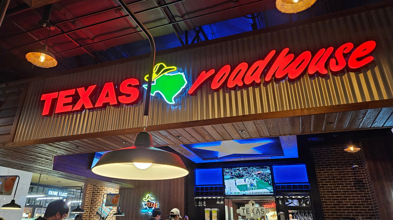 A neon Texas Roadhouse sign inside of a Texas Roadhouse location