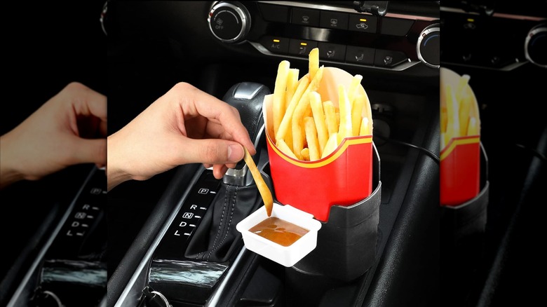 Hand dips french fry into sauce in car