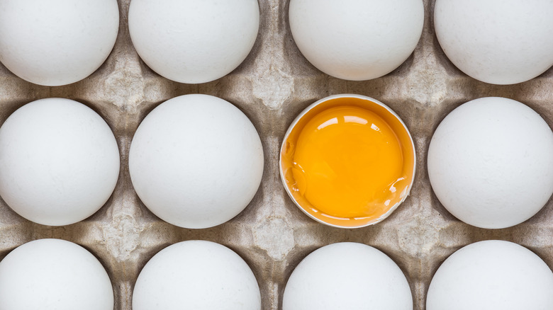Egg yolk among eggs in carton
