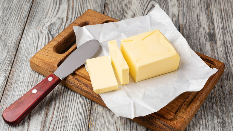 Stick of butter on butter paper and cutting board