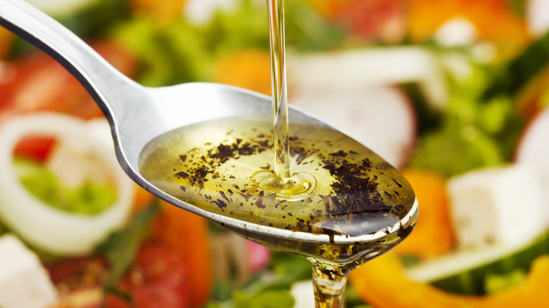 Salad dressing being poured over a spoon