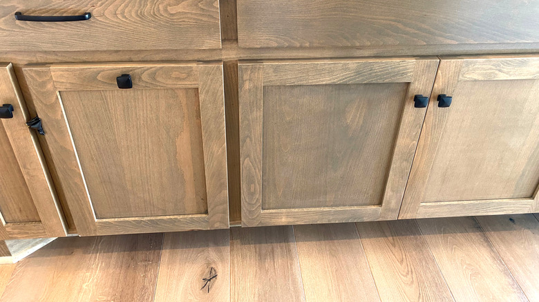 Black washed cabinets above a wooden kitchen floor
