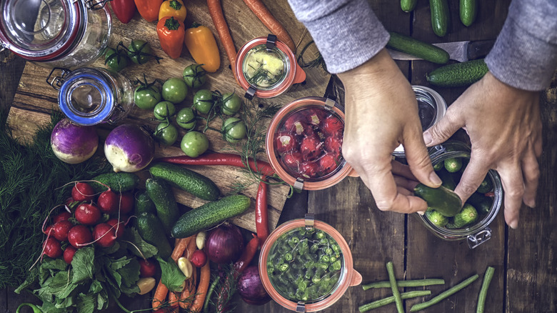 raw vegetables and pickling jars on rustic table