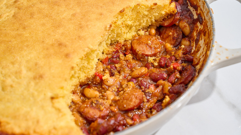 beanie weenie casserole in a skillet with cornbread topping