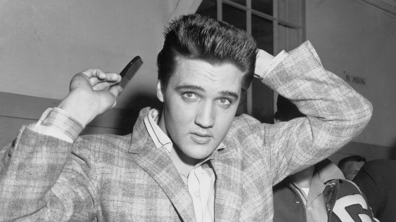 Black and white photo of a young Elvis Presley combing his hair