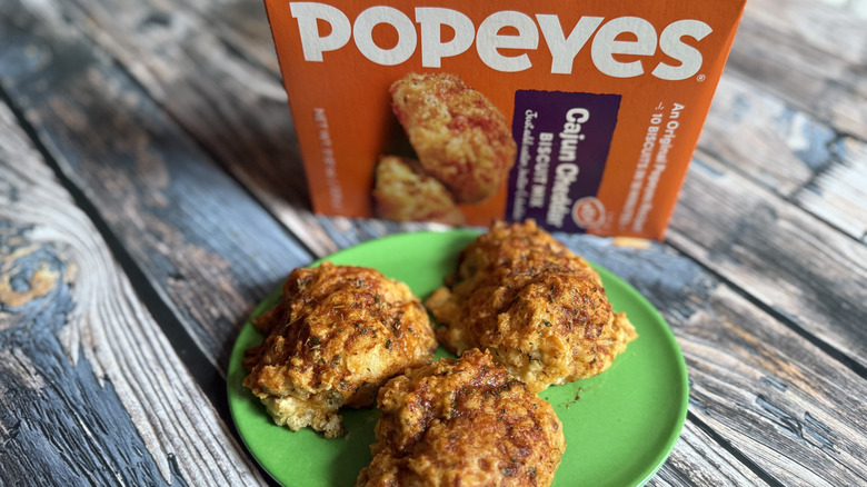 Popeyes Cajun Cheddar box and some biscuits made from it on a green plate
