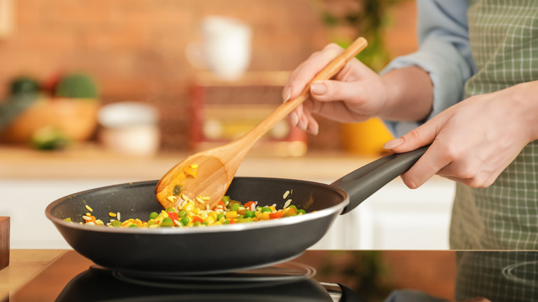 cook stirring pan with spoon