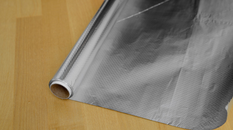A roll of aluminum foil on a wooden table