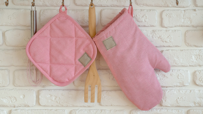 Pink oven mitt and pot holder against a white wall