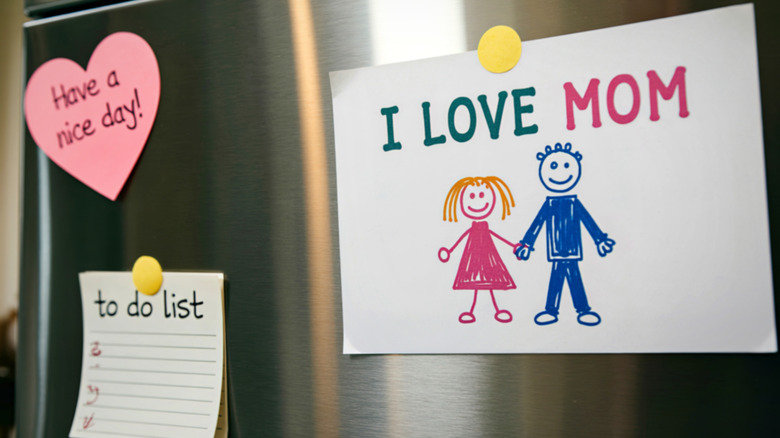 A fridge with a to do list, have a nice day note, and children's drawing reading I love Mom stuck on the fridge door with magnets
