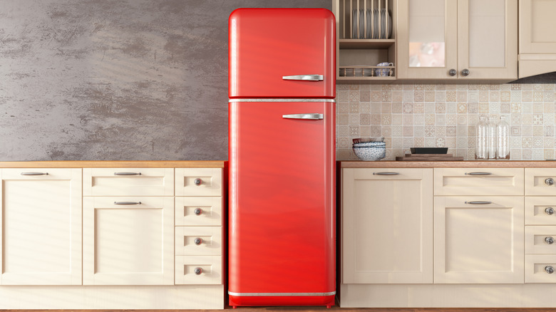 A kitchen with a red vintage freezer-top fridge in the center of all the cabinets