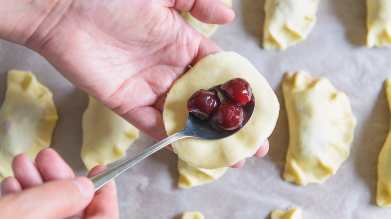 Pierogi being filled with cherries