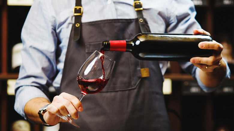 Closeup of a bartender pouring a glass of red wine