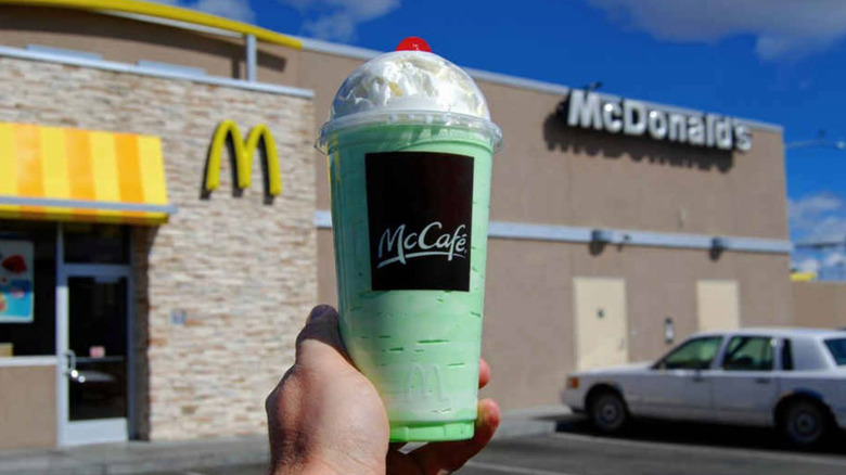 Person holding a Shamrock Shake in front of McDonald's