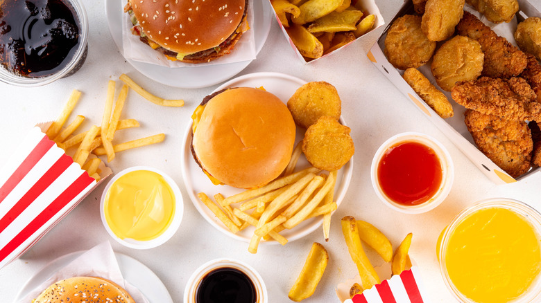 Fast food hamburgers, french fries, chicken nuggets and drinks on a white background