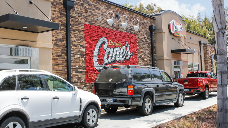 Several cars queueing in a Raising Cane's drive thru