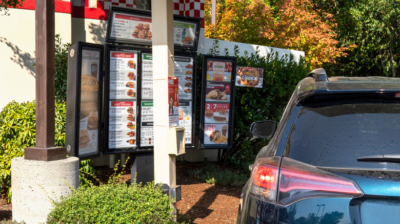 Arby's restaurant drive thru, with a black car next to the menu and order speaker