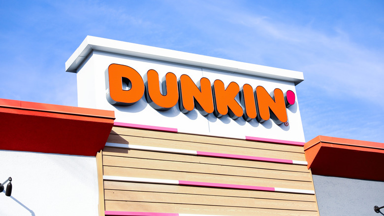 Dunkin' restaurant sign on storefront against a blue sky