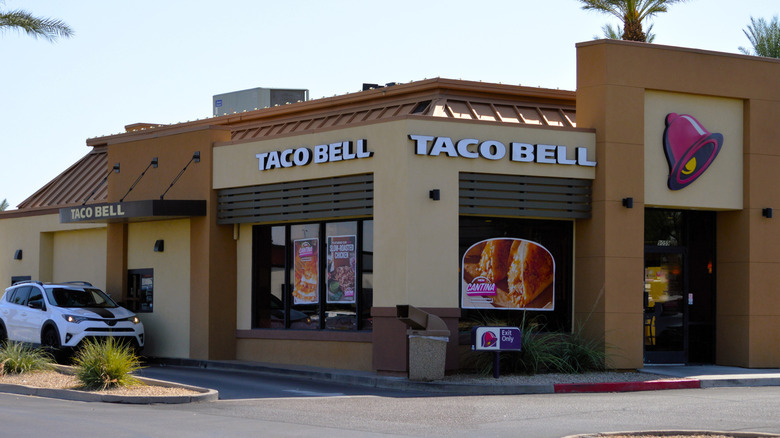 A Taco Bell restaurant with a white car in its drive thru