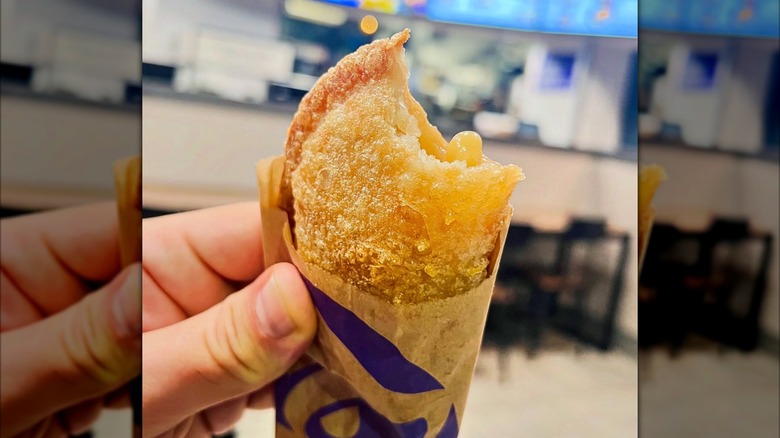 A hand holds a Taco Bell Caramel Apple Empanada