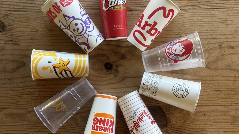 Fast food cups arranged in a circle on a wood table
