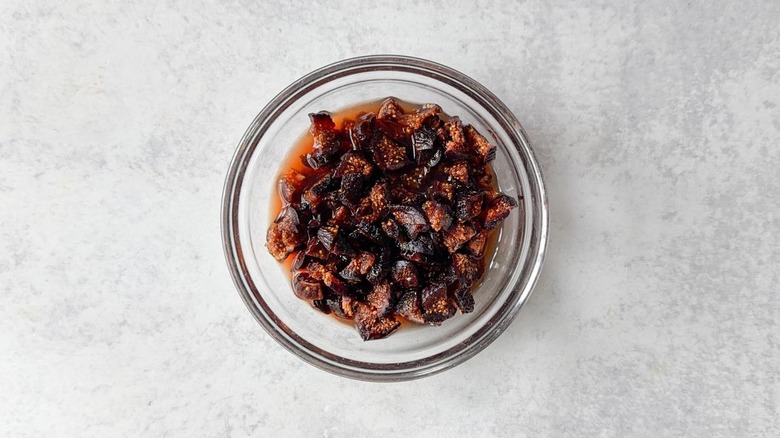 Quartered dried black mission figs soaking in port in glass bowl