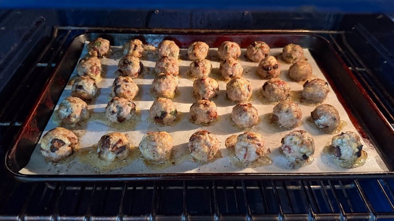 Fig and gorgonzola meatballs baking on parchment-lined baking sheet in oven