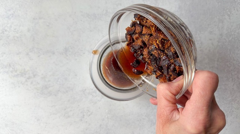 Draining port from soaked dried figs in glass bowl