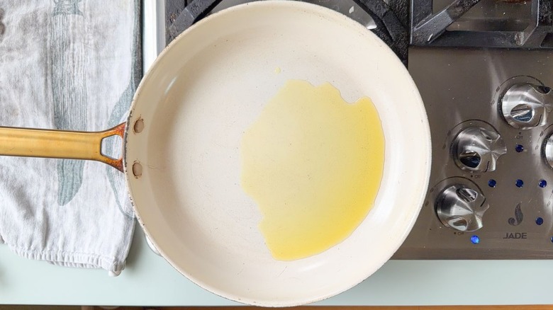 Large white skillet with olive oil on stovetop