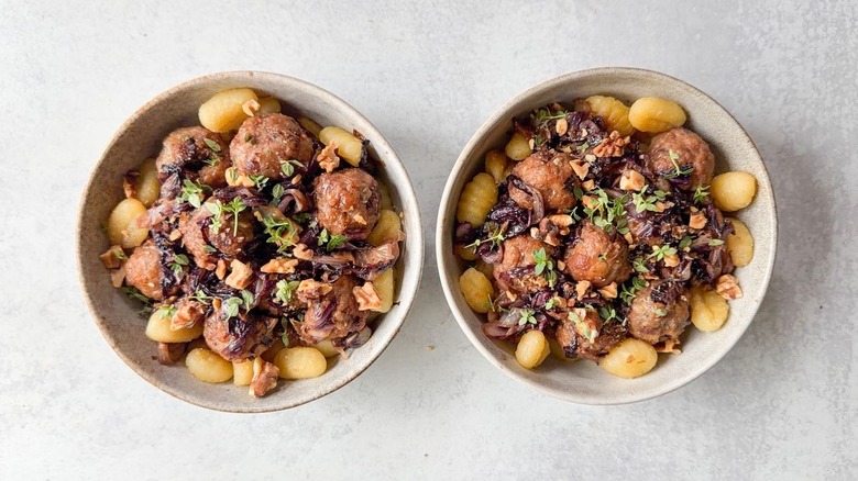 Fig and gorgonzola meatballs with radicchio in serving bowls, garnished with toasted walnuts and fresh thyme
